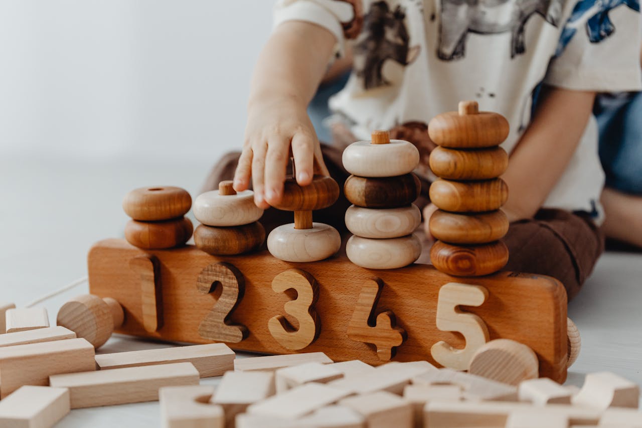Childs hand interacting with wooden educational toys and number blocks indoors.